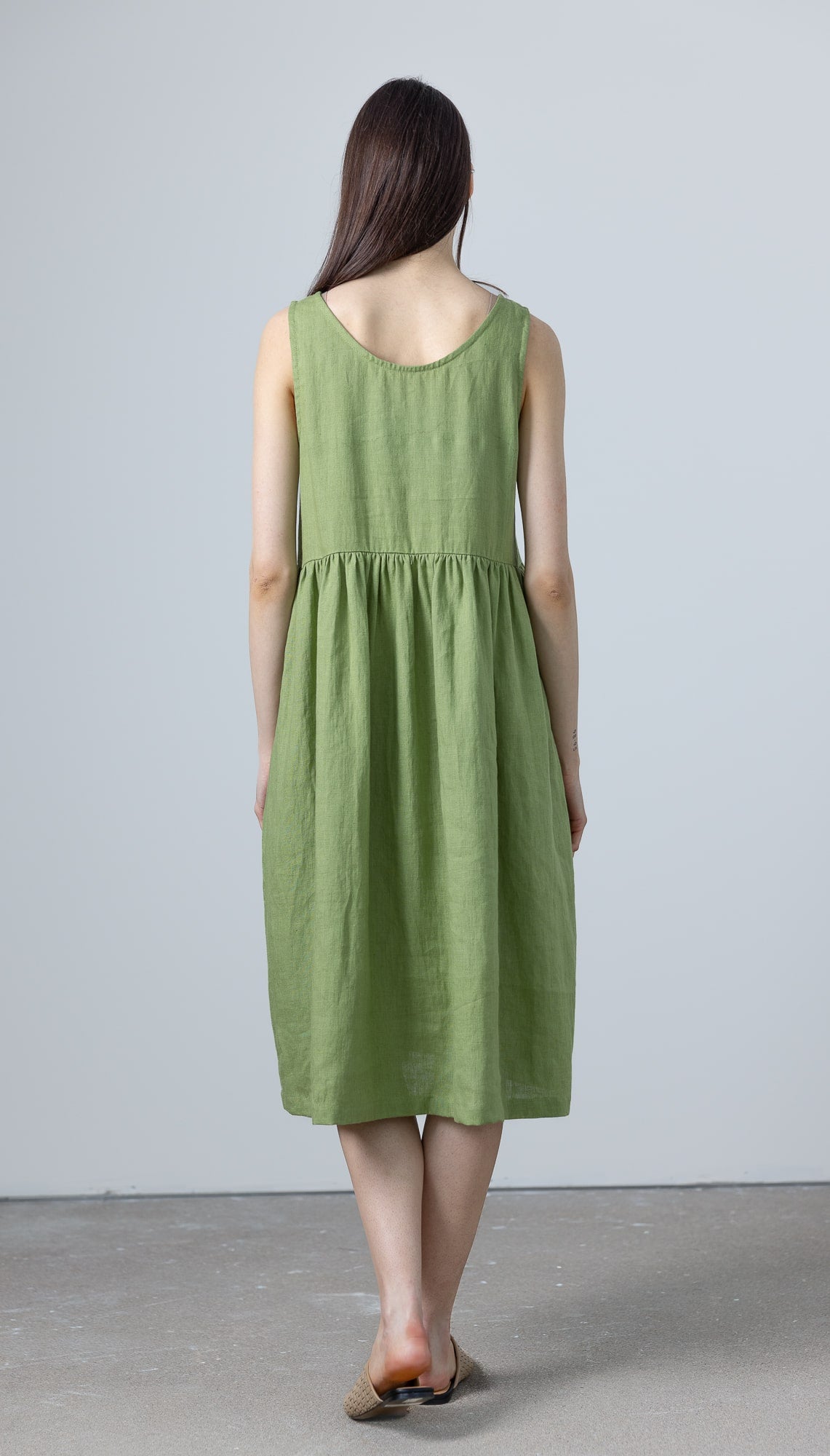 Back view of MinimalisticLinen a line green dress showing the relaxed empire waist and flowy midi length.