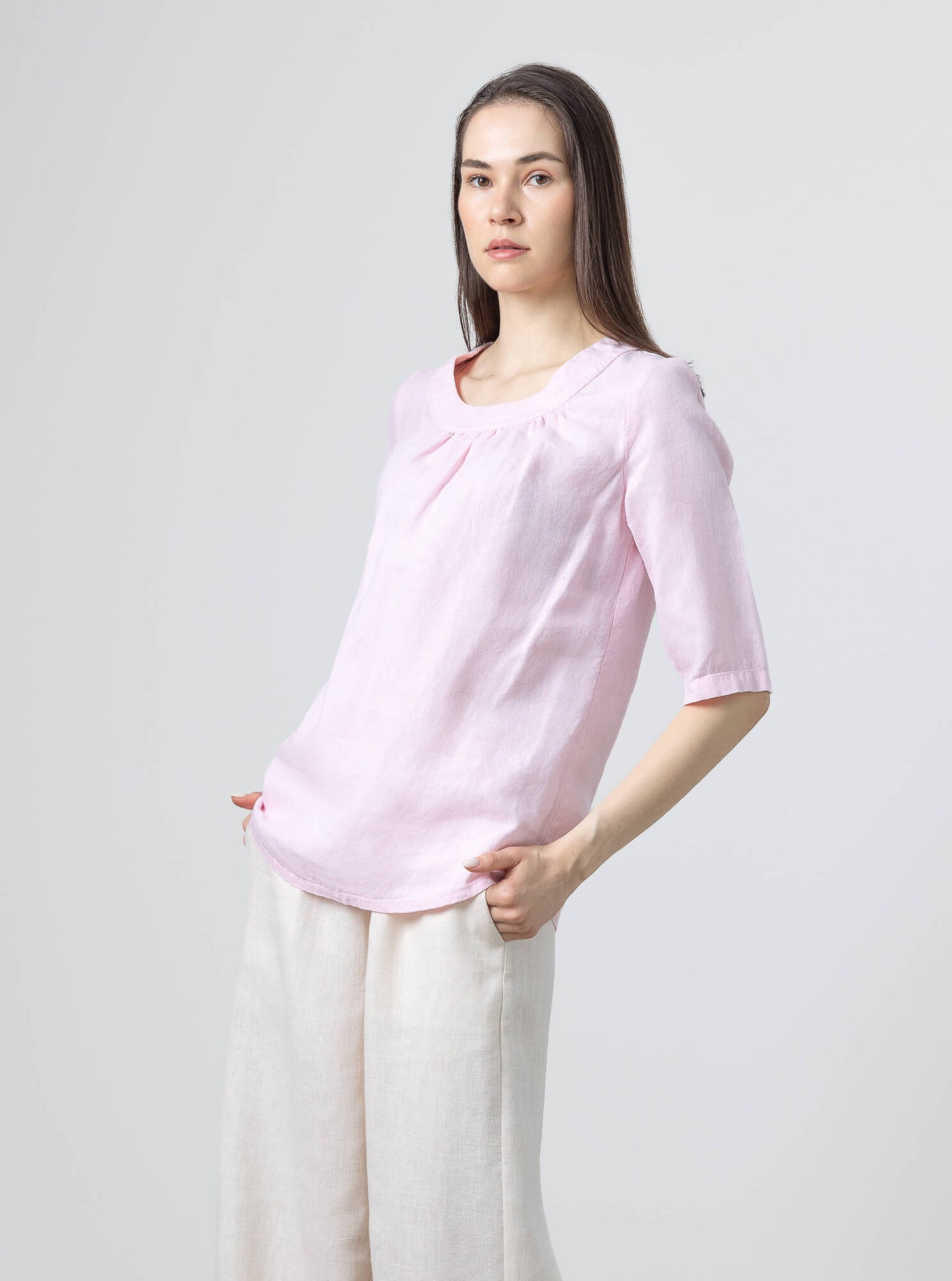 Relaxed fit blush pink linen blouse with gathered neckline and elbow-length sleeves.