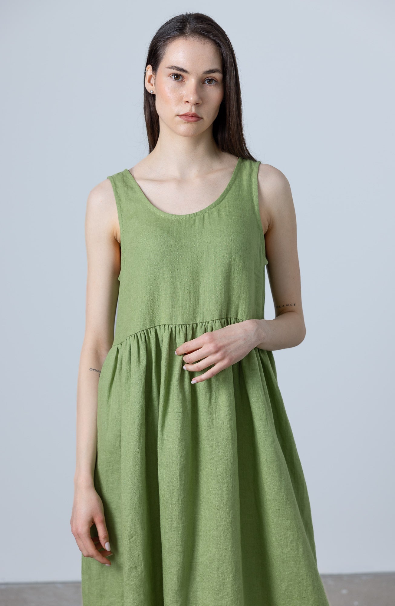 Close‑up of MinimalisticLinen linen green dress with scoop neckline and gathered skirt detail.