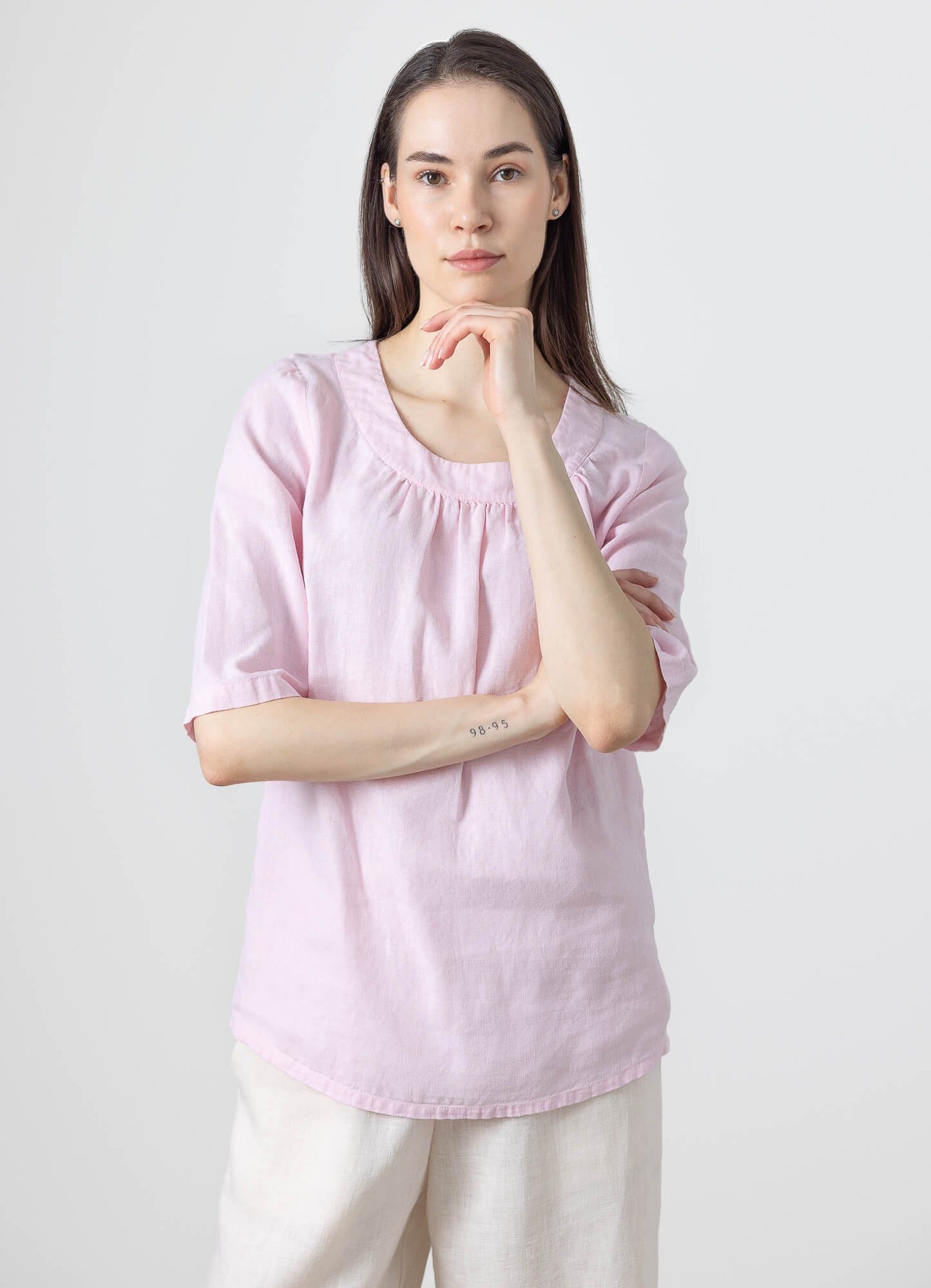 Elegant women's pink linen blouse with a round gathered neckline and minimalist style.