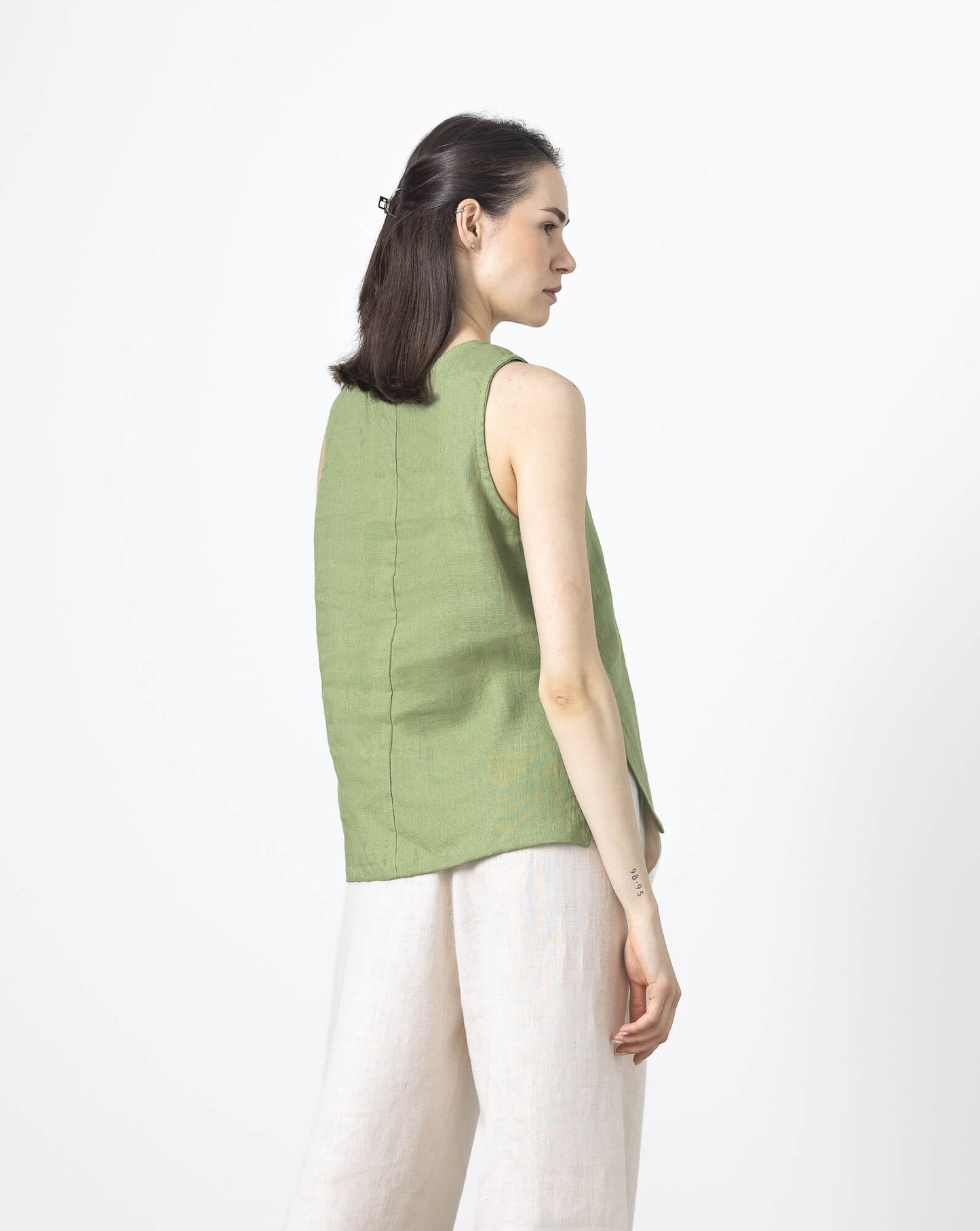 Back view of women's green linen V-neck blouse made from breathable linen fabric.