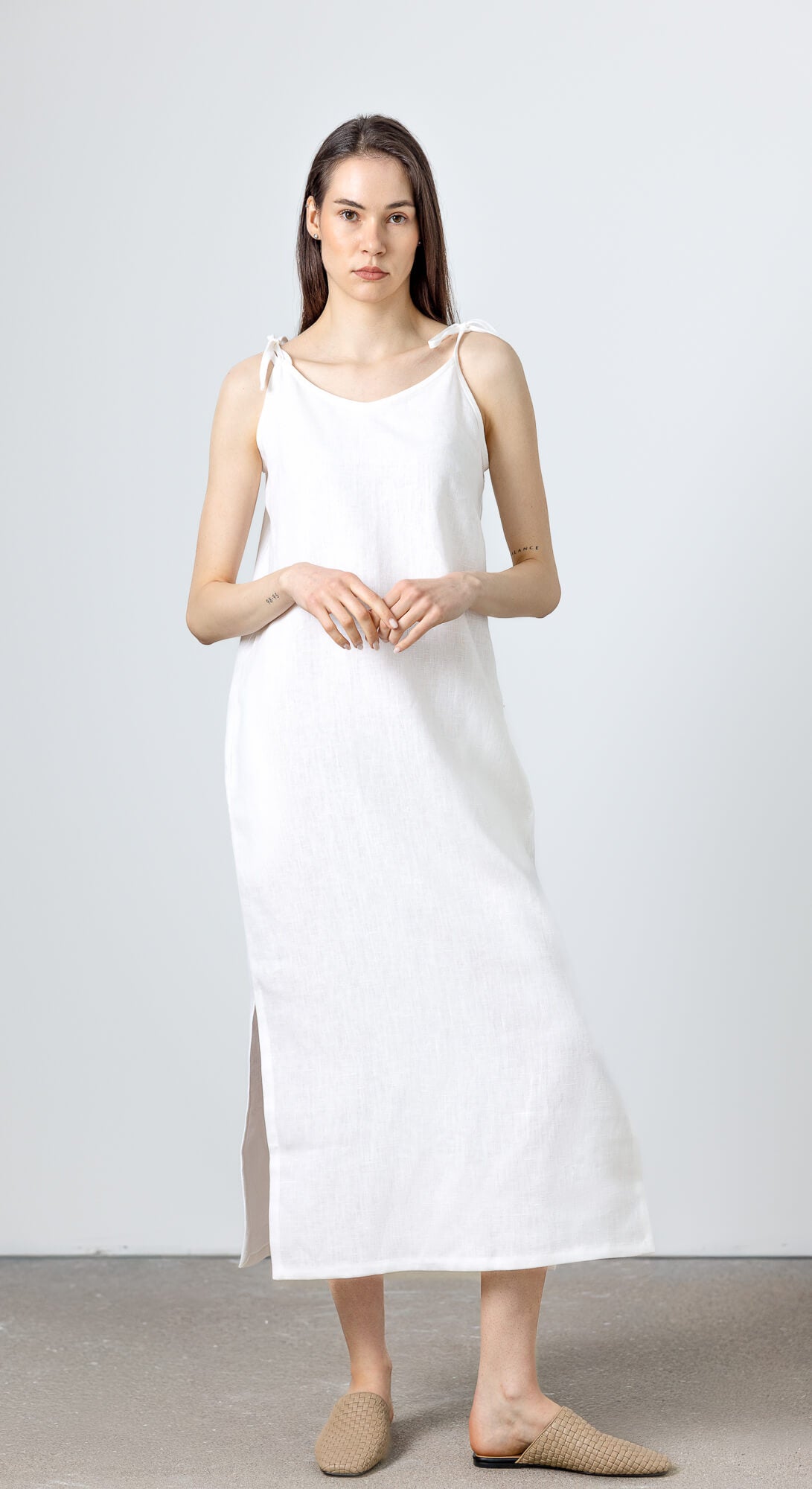 Sleeveless white linen dress with soft relaxed fit and side slit