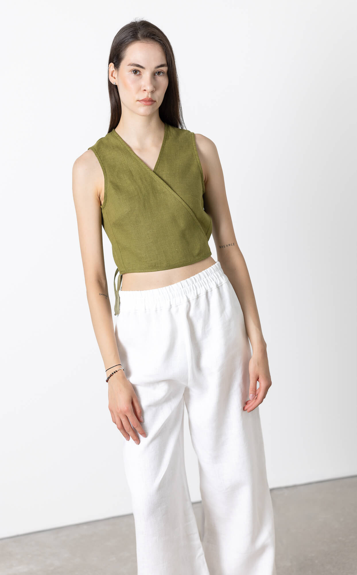 Close-up front view of women's sleeveless linen wrap crop top made from breathable OEKO-TEX® certified linen with adjustable side tie for minimalist summer wardrobe