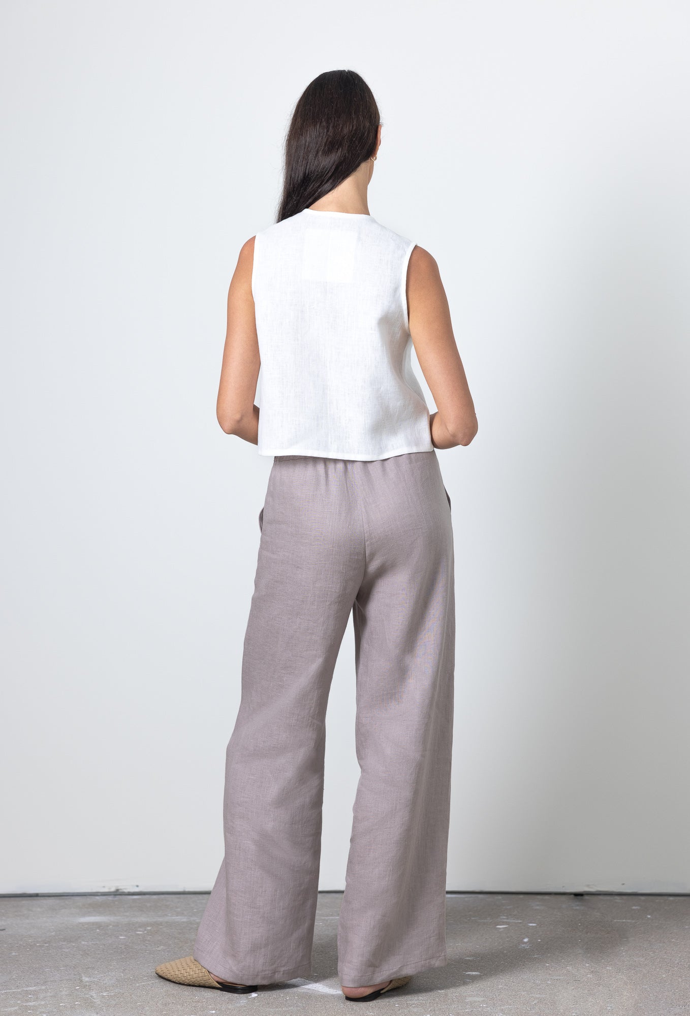 Back view of a sleeveless linen tie front top styled with wide leg trousers, breathable and elegant linen outfit
