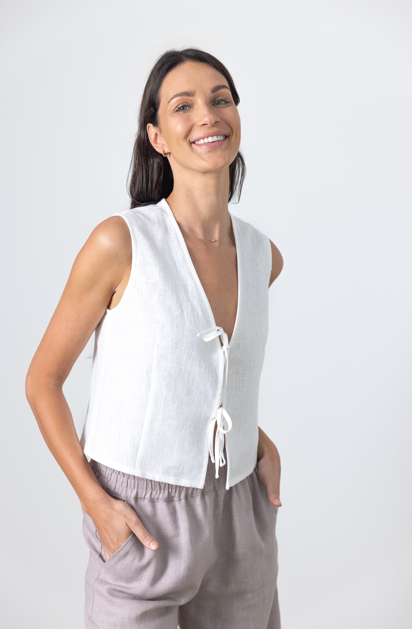 Close-up of a woman in a minimalist white linen tie front blouse, showing front tie detail and relaxed fit.