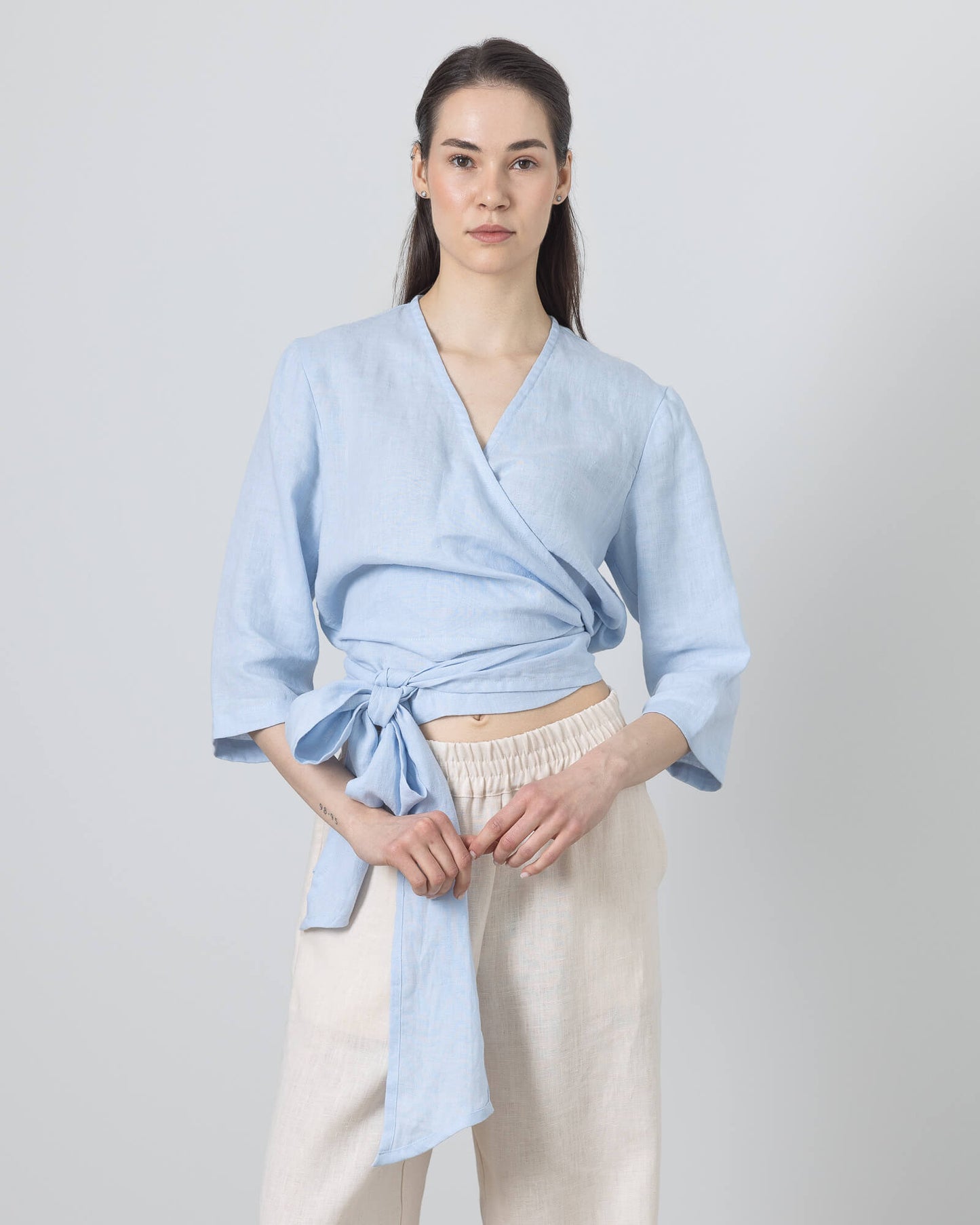Linen wrap top for women in soft blue – relaxed fit blouse with tie waist and 3/4 sleeves, styled with wide-leg linen pants