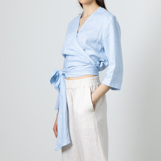 lose-up of a linen wrap top in light blue, tied at the waist – cropped summer blouse
