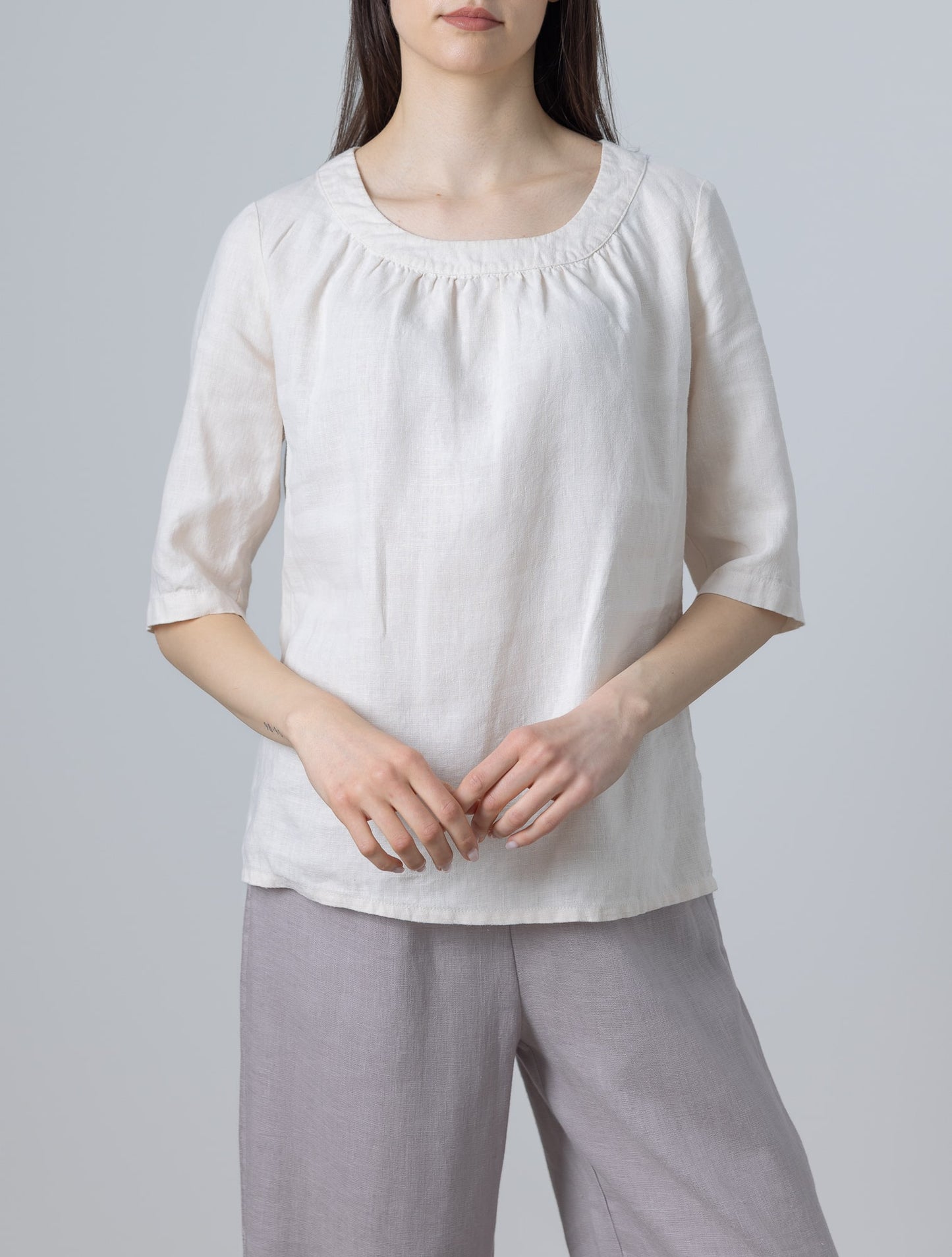 Model wearing Ladies White Linen Blouse Lily with ruffle neckline and half sleeves, front view