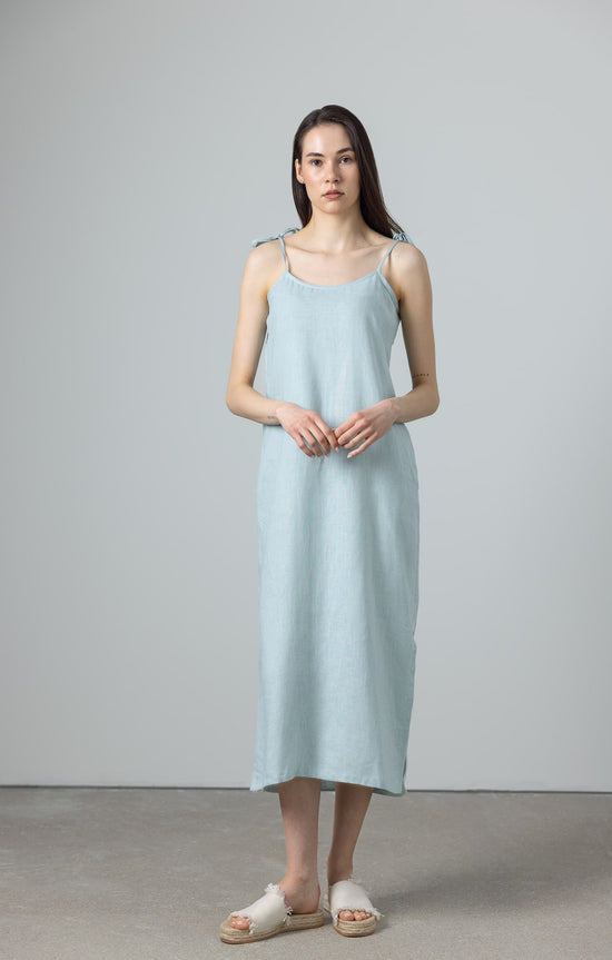 Model wearing green linen slip dress with tie straps and A-line silhouette, a versatile green maxi linen dress for minimalist style