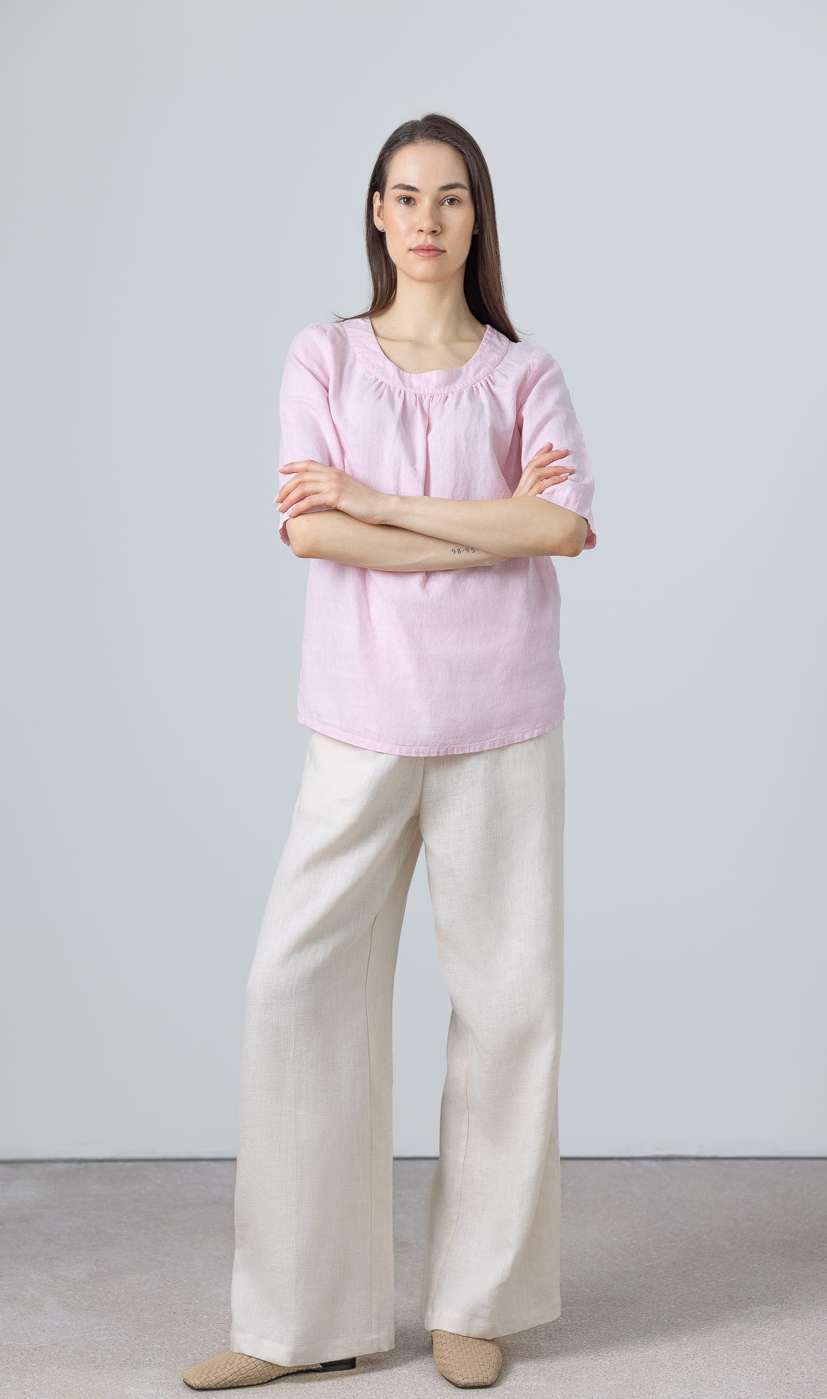 Model styling a lightweight pink linen T-shirt for women with casual wide-leg trousers
