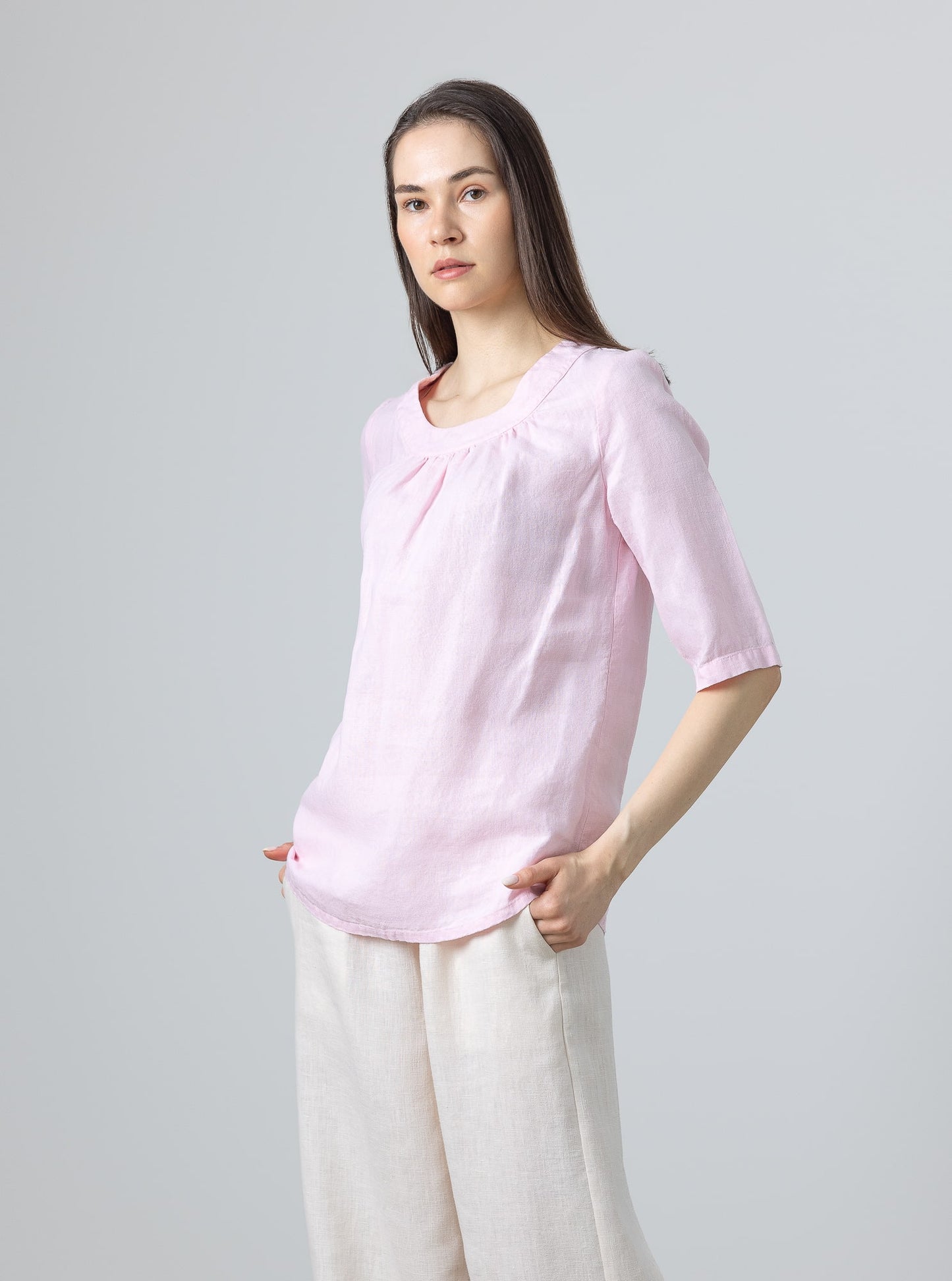 Minimalist pink linen blouse with feminine gathered detail at neckline – worn with beige linen trousers