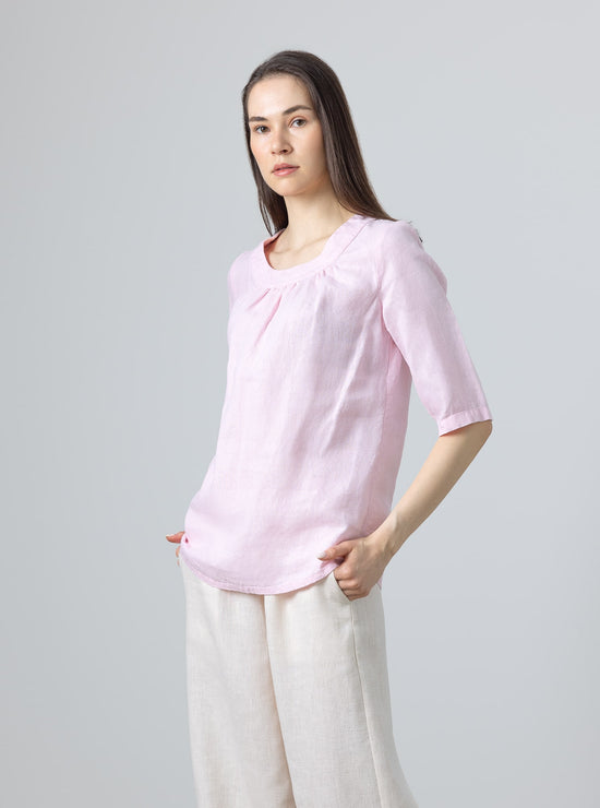 Minimalist pink linen blouse with feminine gathered detail at neckline – worn with beige linen trousers