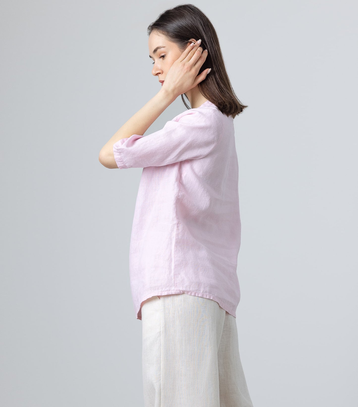 Side profile of woman in ruffle neck pink linen blouse and wide-leg natural linen pants