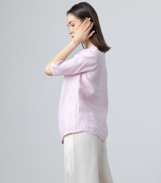 Side profile of woman in ruffle neck pink linen blouse and wide-leg natural linen pants