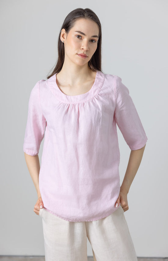 Woman wearing pink linen blouse with ruffle neck and elbow-length sleeves – relaxed minimalist fit