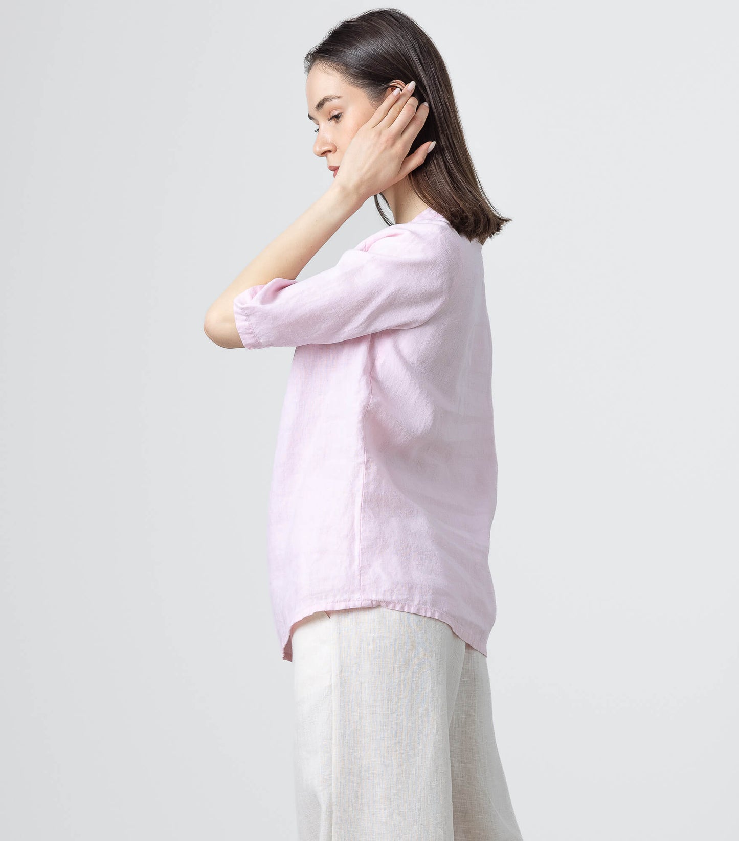 Side profile of a women's pink linen blouse featuring a gathered neckline and relaxed silhouette.