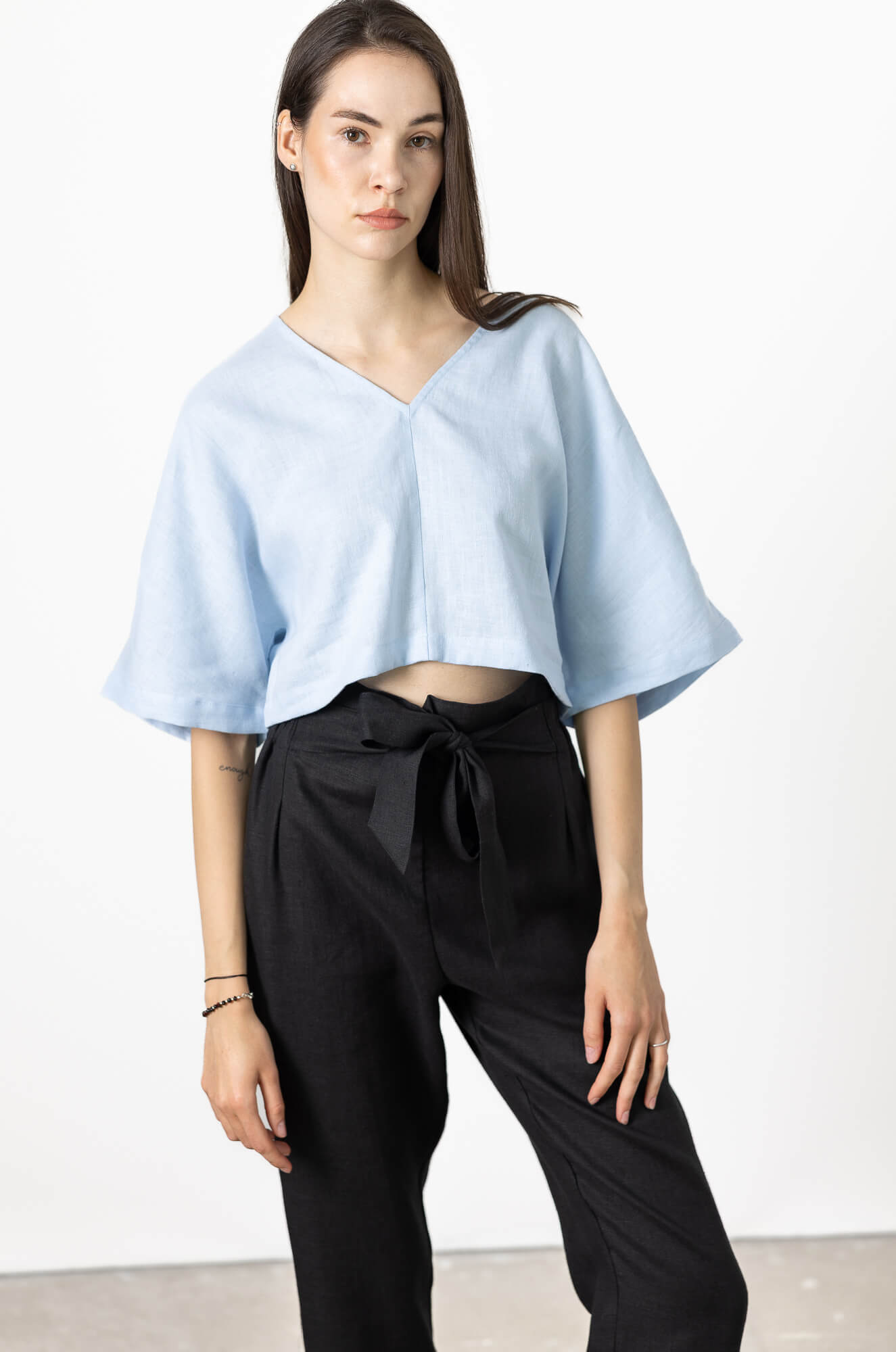 Woman wearing light blue loose fit linen top and black pants