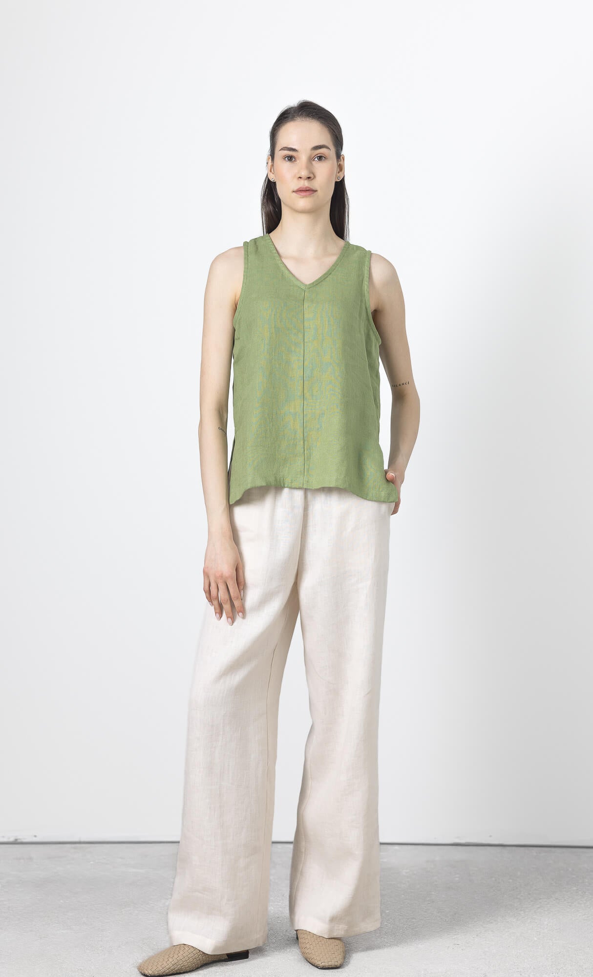 Full length view of women's green linen sleeveless blouse paired with wide leg linen pants.