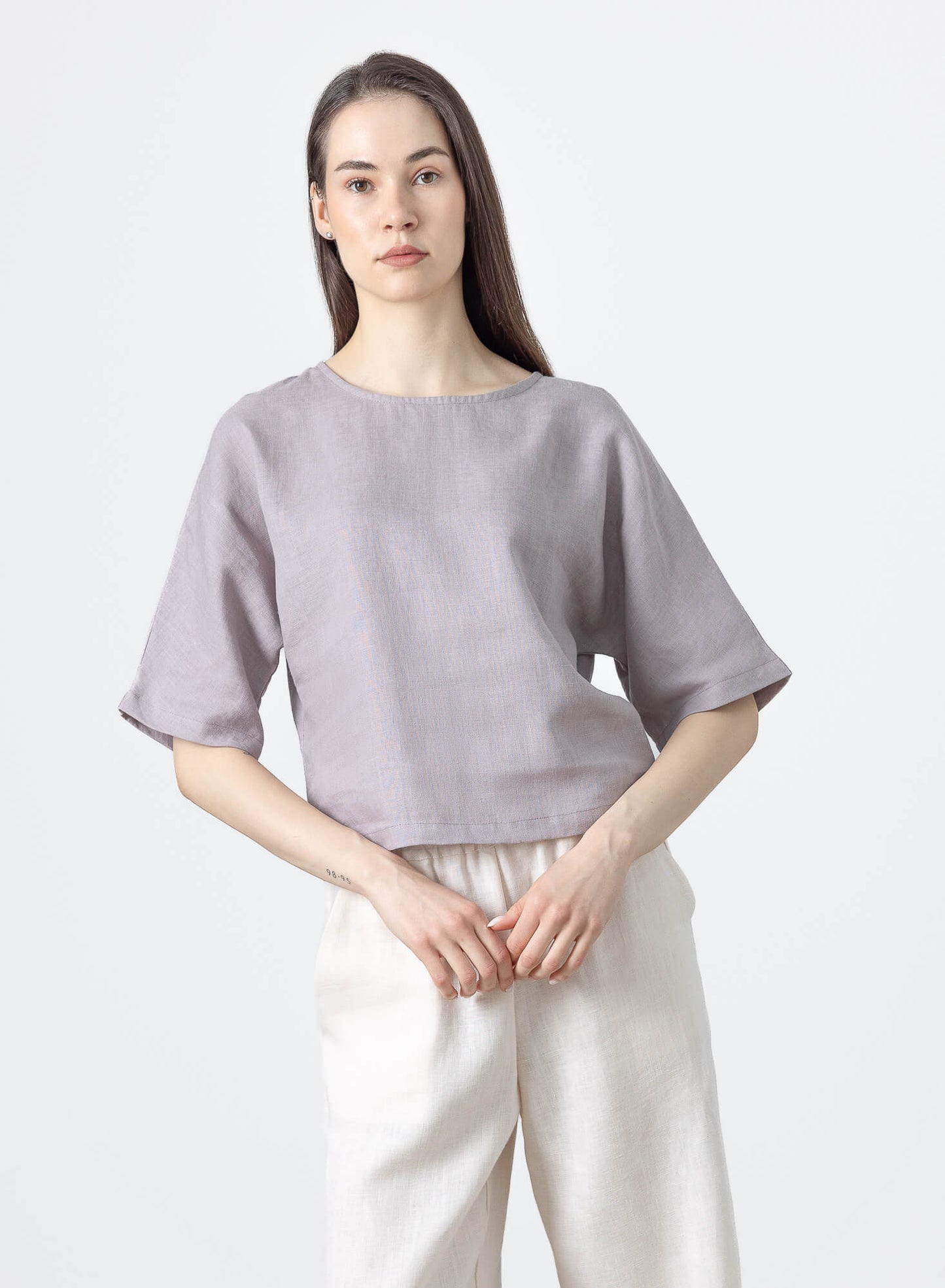 Woman wearing a relaxed fit linen crop blouse with short sleeves and a minimalist silhouette