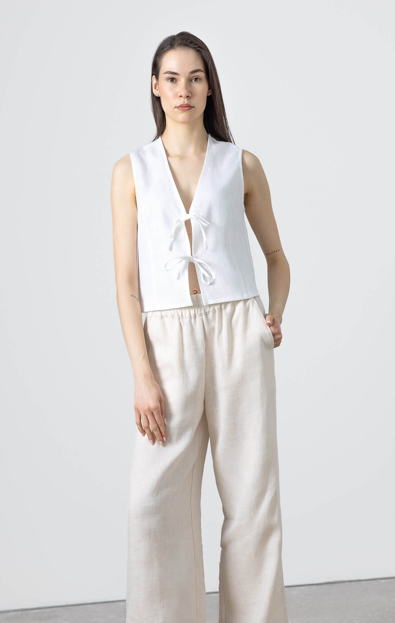 Woman wearing a sleeveless linen tie front vest styled with relaxed wide leg linen pants