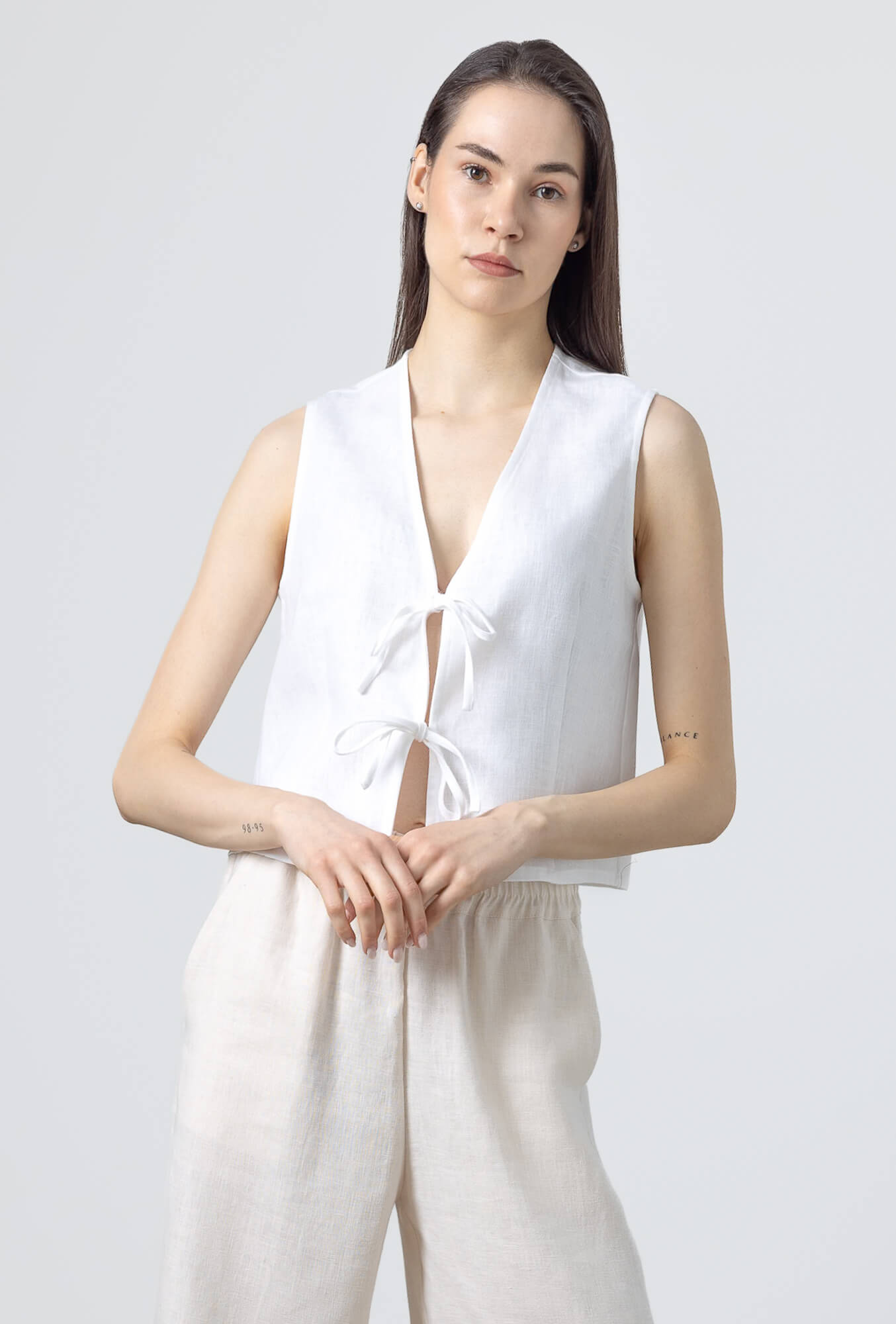 Woman wearing a minimalist linen tie front vest with a relaxed sleeveless silhouette