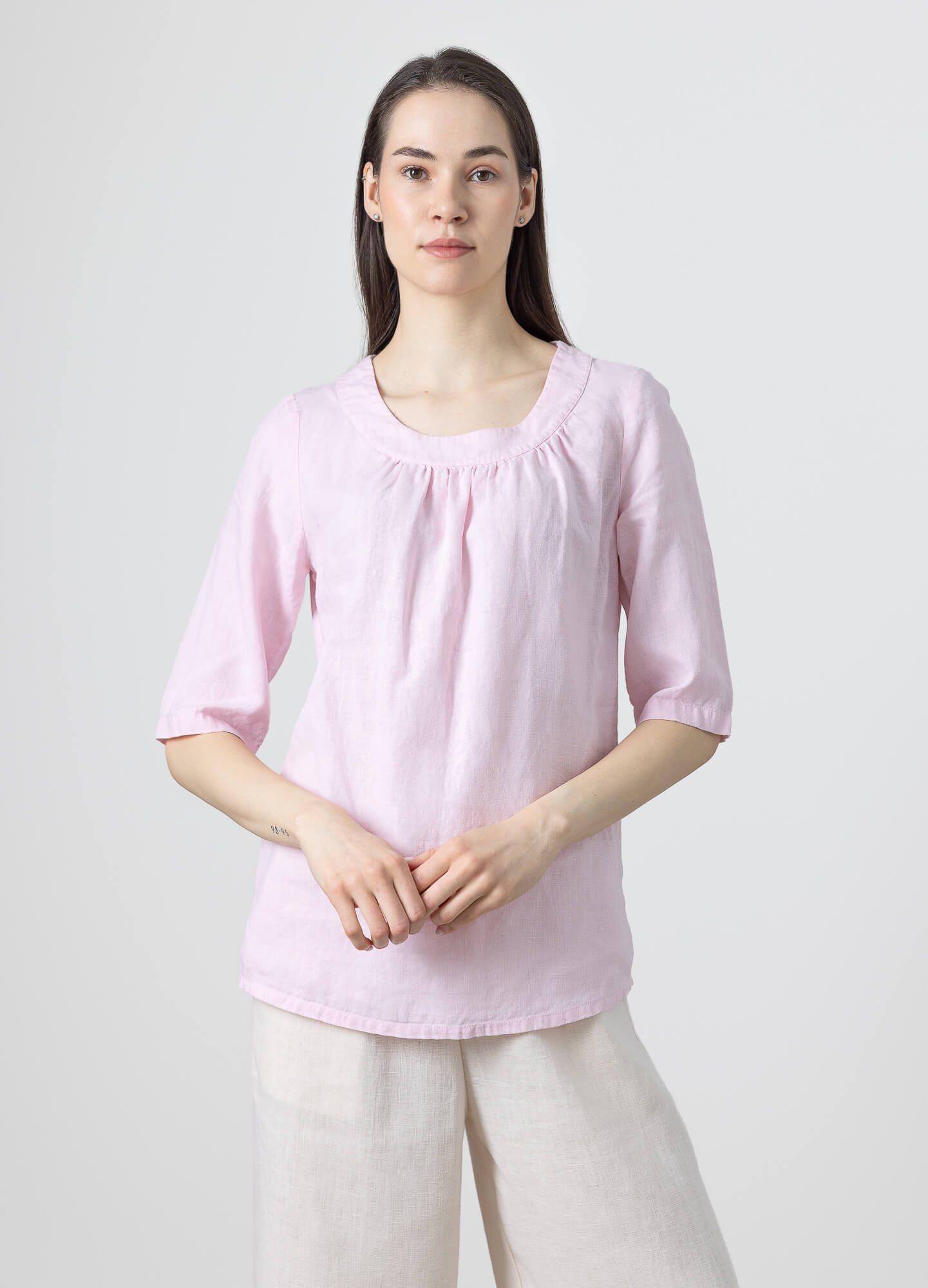 Front view of a blush pink linen top with a gathered round neckline and breathable linen fabric.