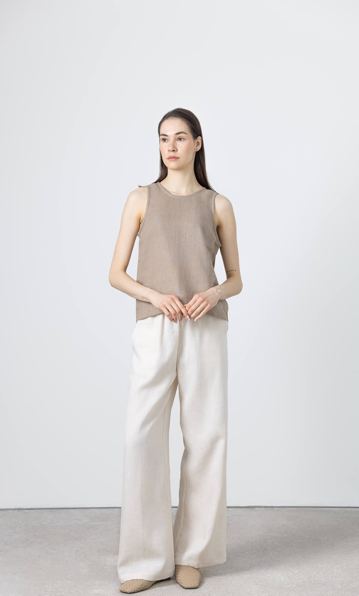 Full length view of women's brown linen sleeveless blouse styled with wide leg linen pants.