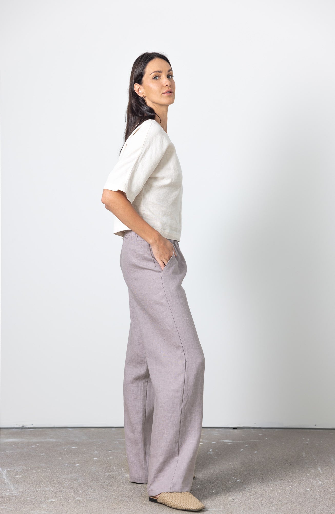 Woman wearing wide leg linen pants in soft grey with short sleeve top – side view